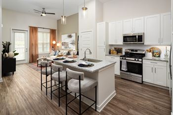 A kitchen with a white island and a dining table with chairs.